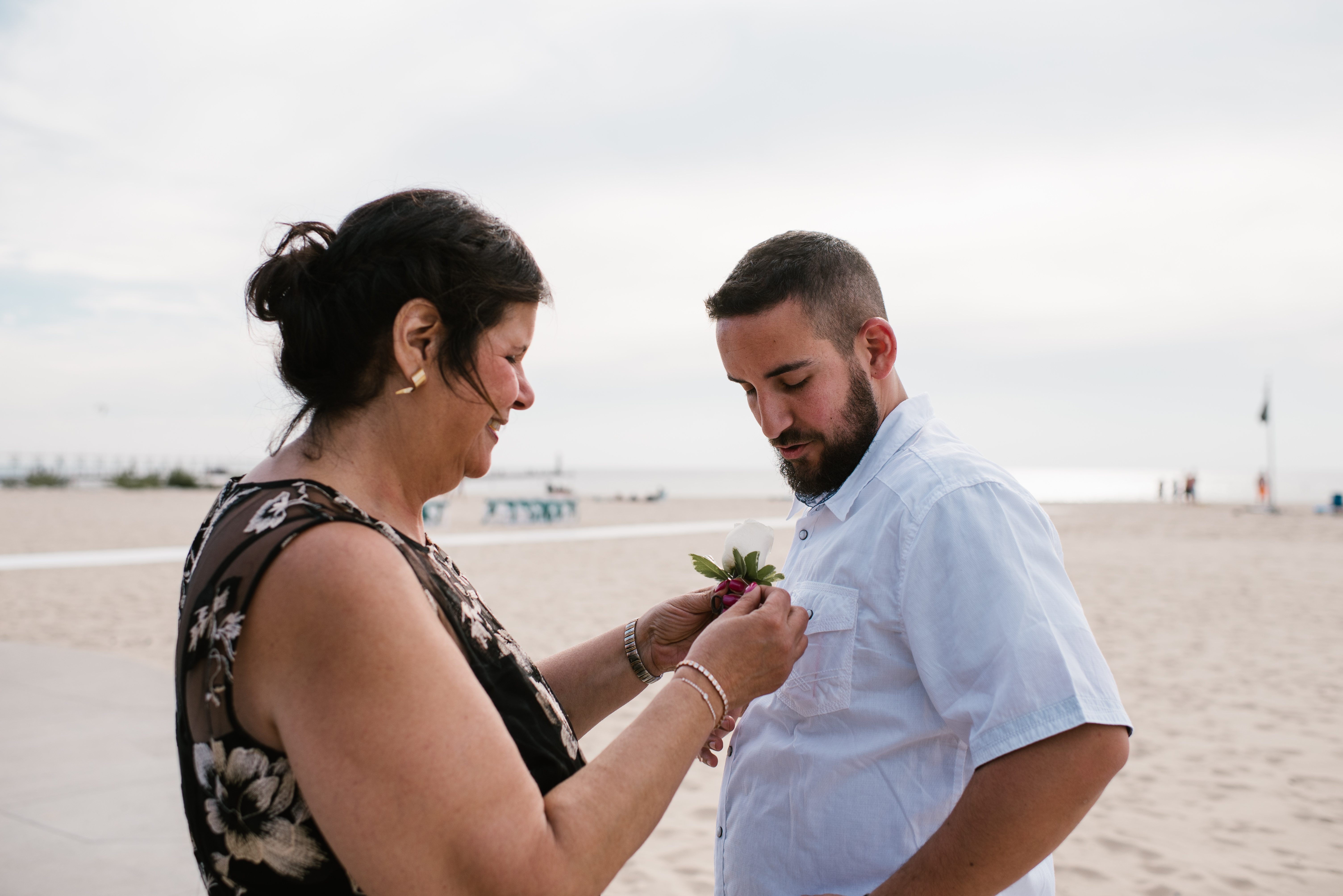 mom pinning a bout on son's shirt at his north beach wedding